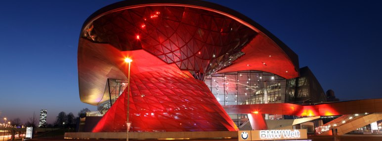 Die BMW Welt rot beleuchtet bei Nacht - BAHNHIT.DE, &copy; M&uuml;nchen Tourismus, Foto: S. M&uuml;ller